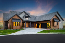 A home with natural wood siding and dark garage doors photographed at dusk by North Carolina Architectural Photographer
