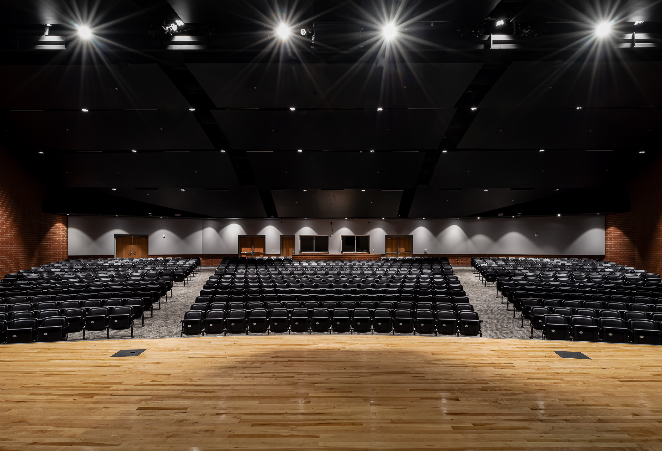 A large auditorium with black seats and captivating spotlights captured by professional architectural photographer in Charlotte.