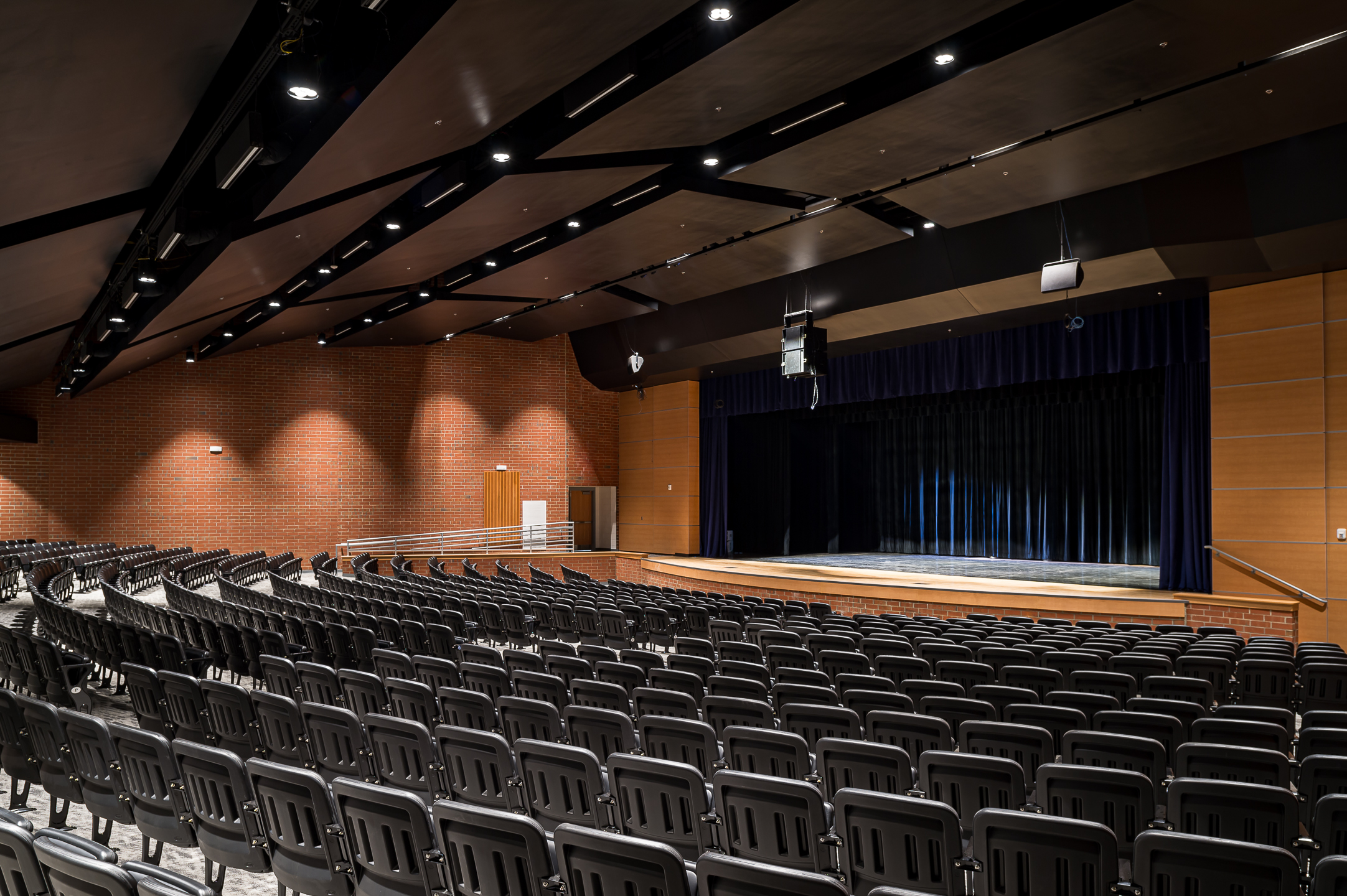 A large auditorium with rows of chairs and a stage, captured by professional architectural photographer