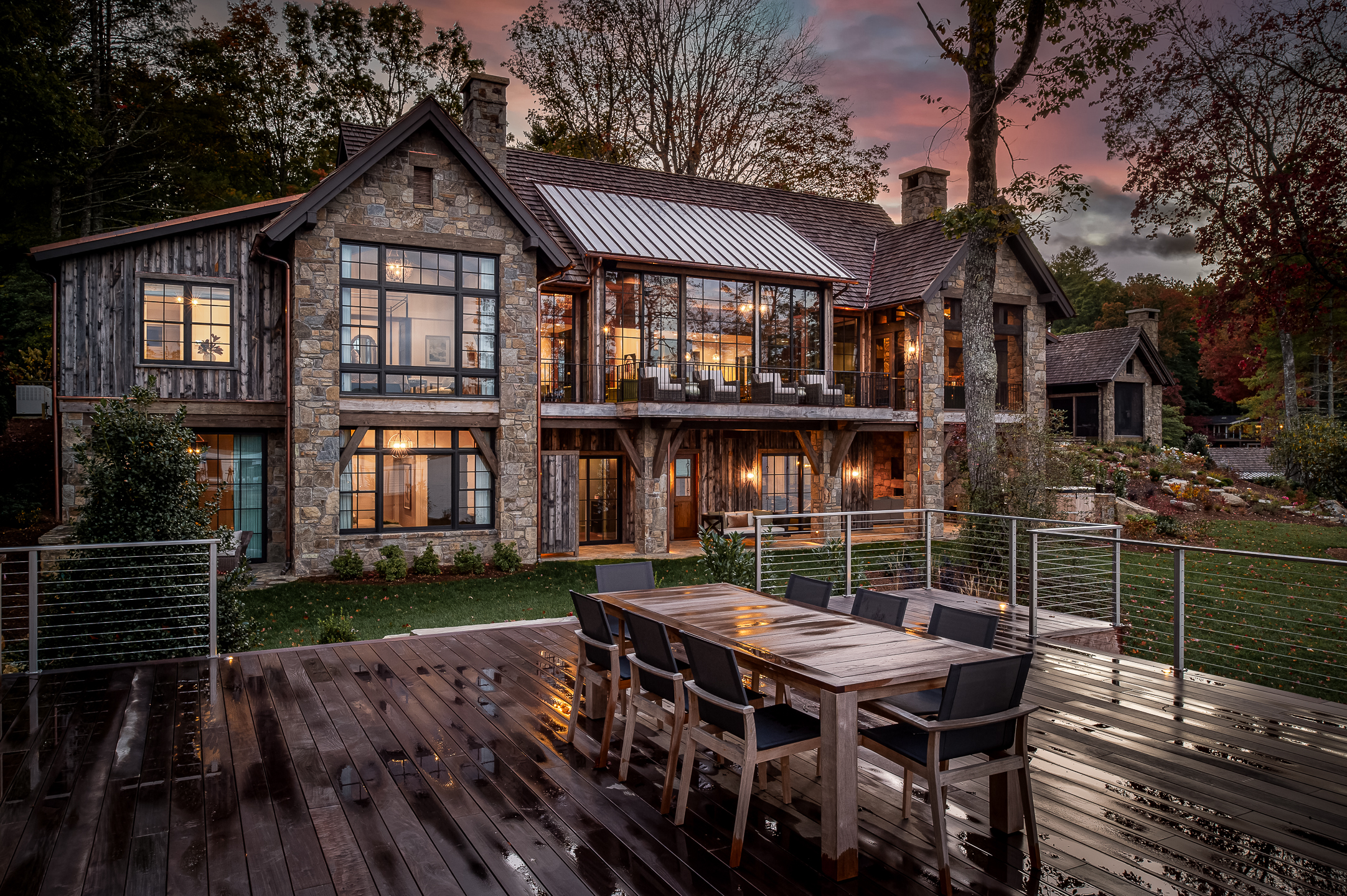 A home with a deck and outdoor dining area at dusk. captured by professional architectural photographer in Asheville, North Carolina