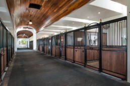 a long hallway with wooden stalls and wooden doors.