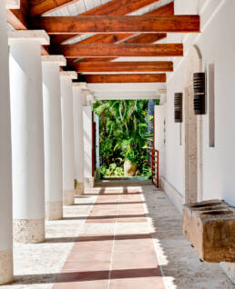 a white hallway with wooden pillars and a wooden bench.