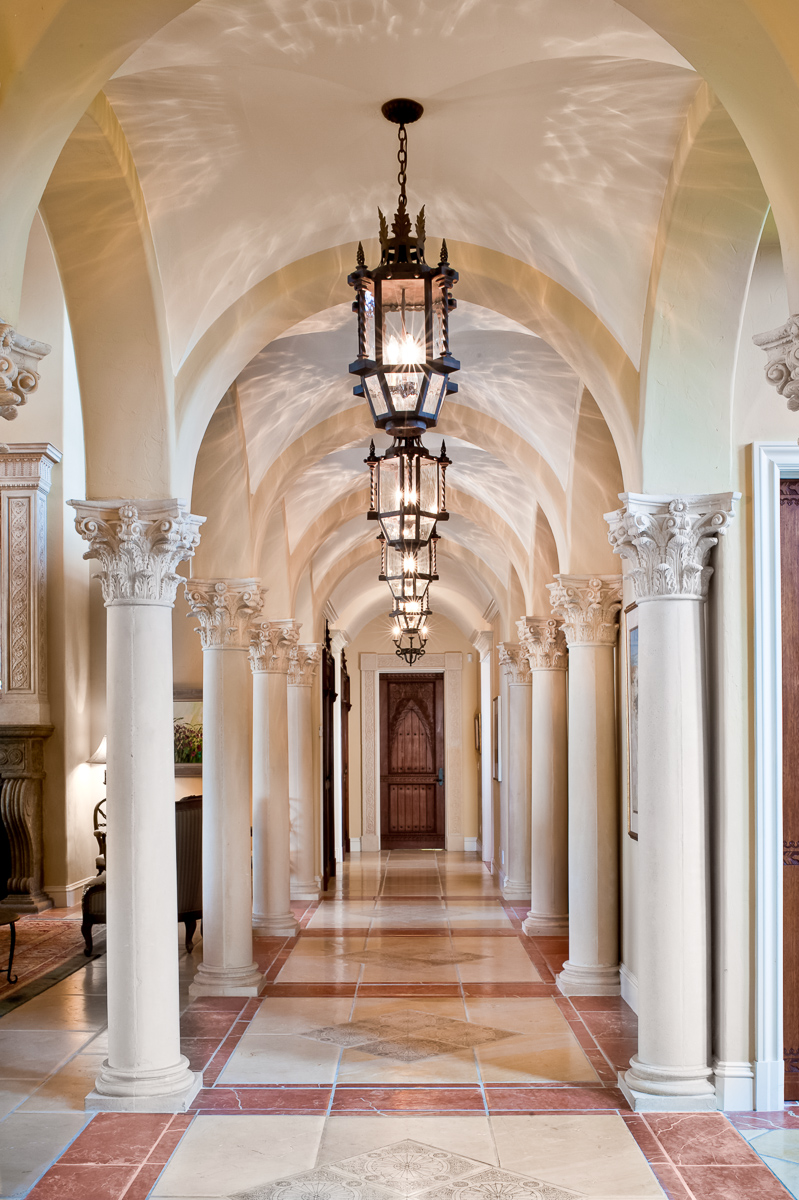 a hallway with columns and a chandelier.
