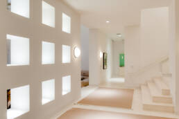 a hallway with white walls and a staircase.