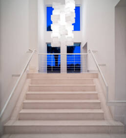 a white staircase with a blue light hanging above it.