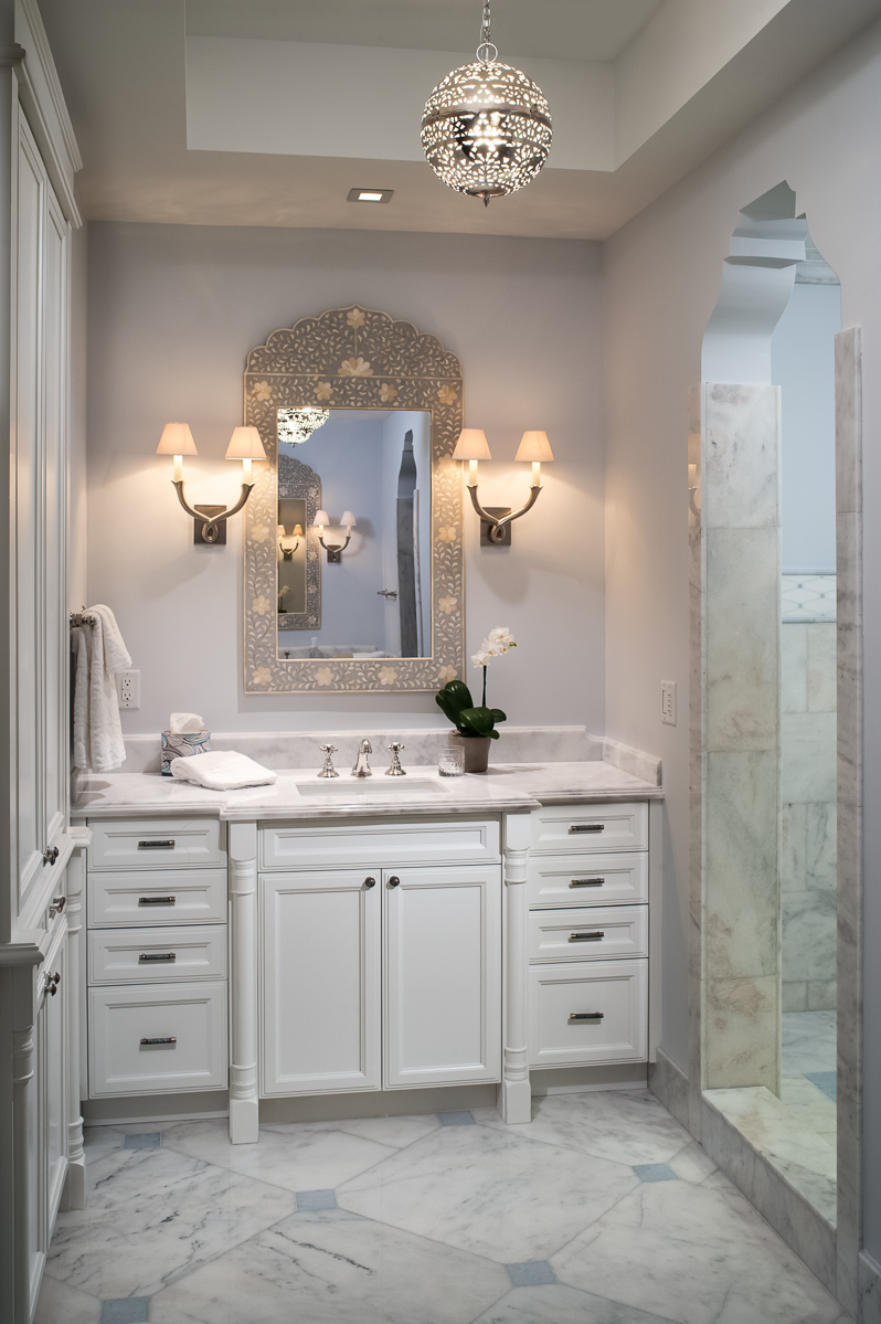 a white bathroom with marble floors and a chandelier.