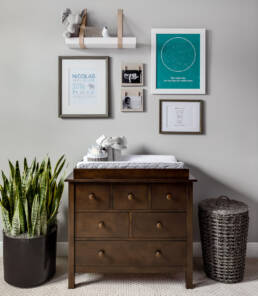 a nursery with a changing table and framed pictures.