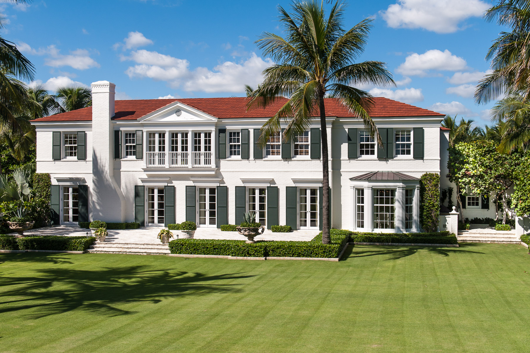 a large white house with palm trees in the lawn.