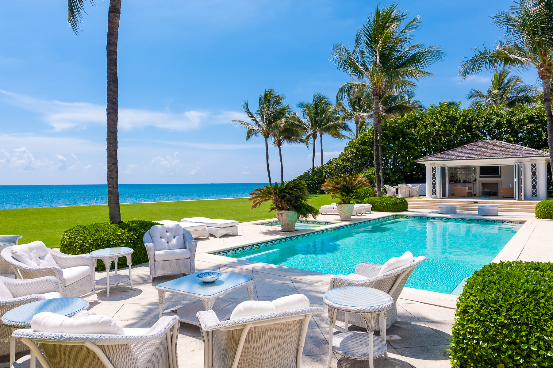a pool with white furniture and palm trees.