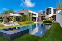a modern home with a swimming pool and lawn.
