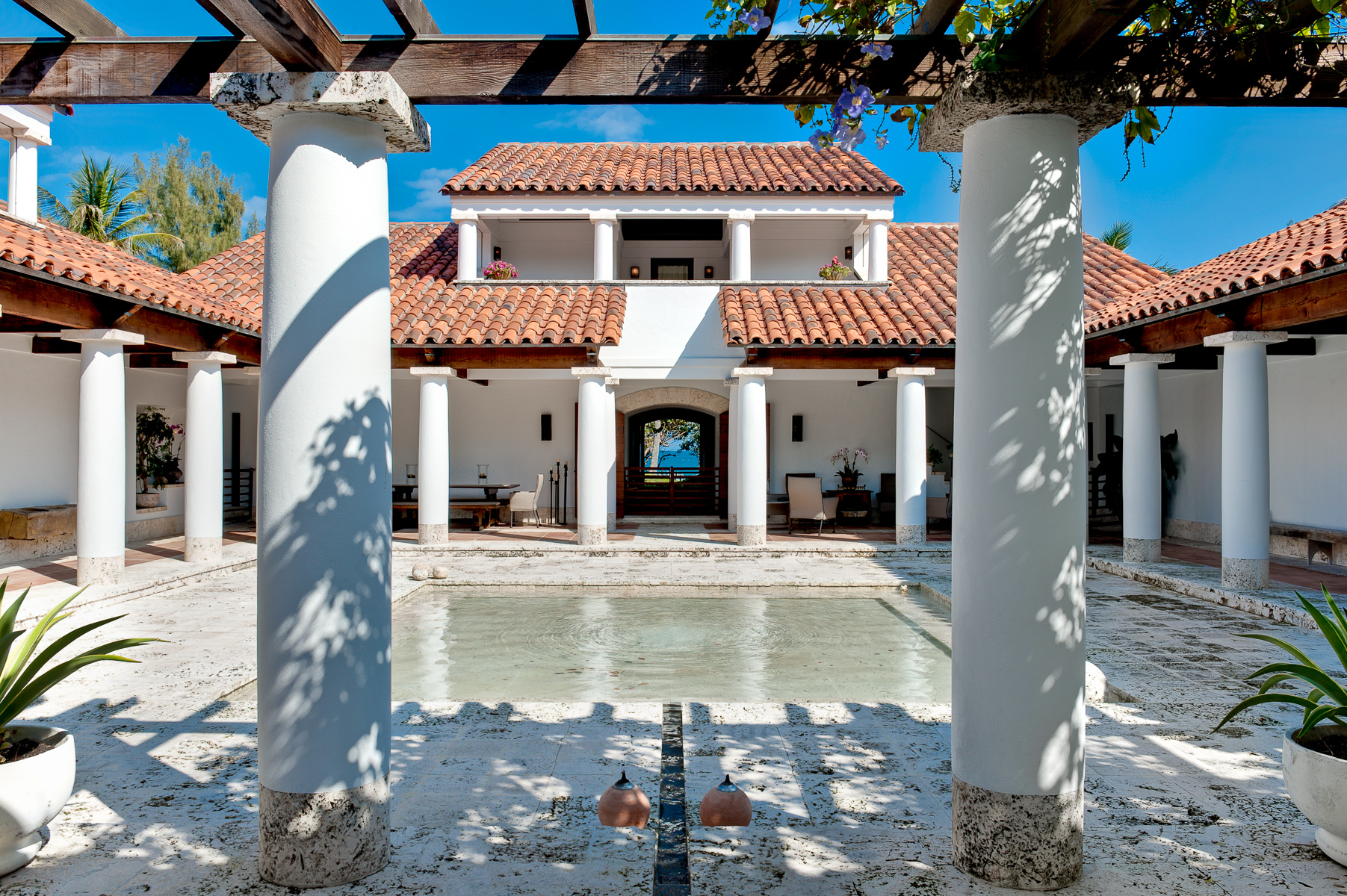 the courtyard of a house with a pool and pillars.
