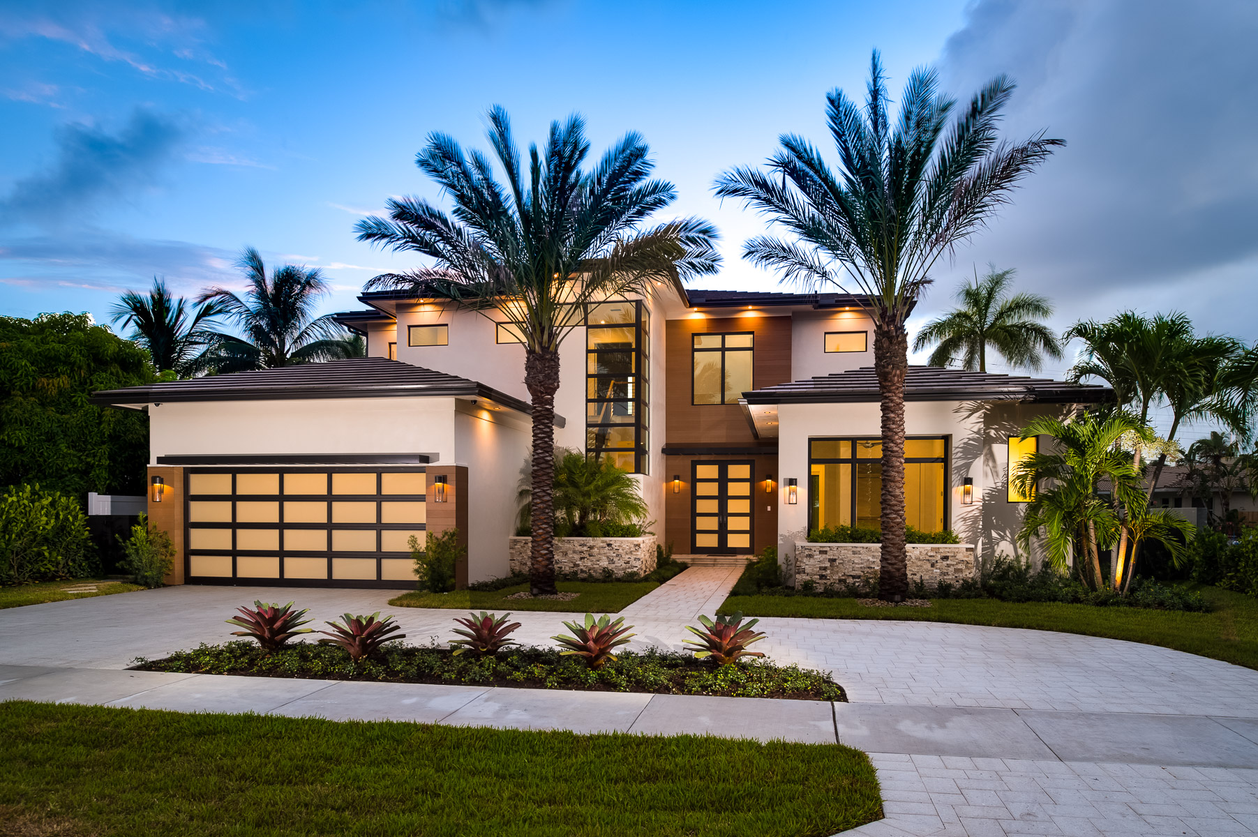 a modern home with palm trees and driveway.