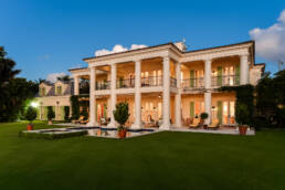 a large mansion in the middle of a lush green lawn.