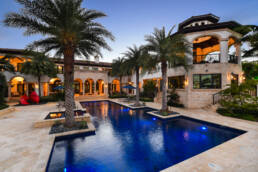a mansion with a pool and palm trees.