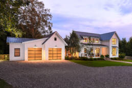 a white home with two garages at dusk.