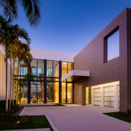 a modern home with palm trees and a driveway.