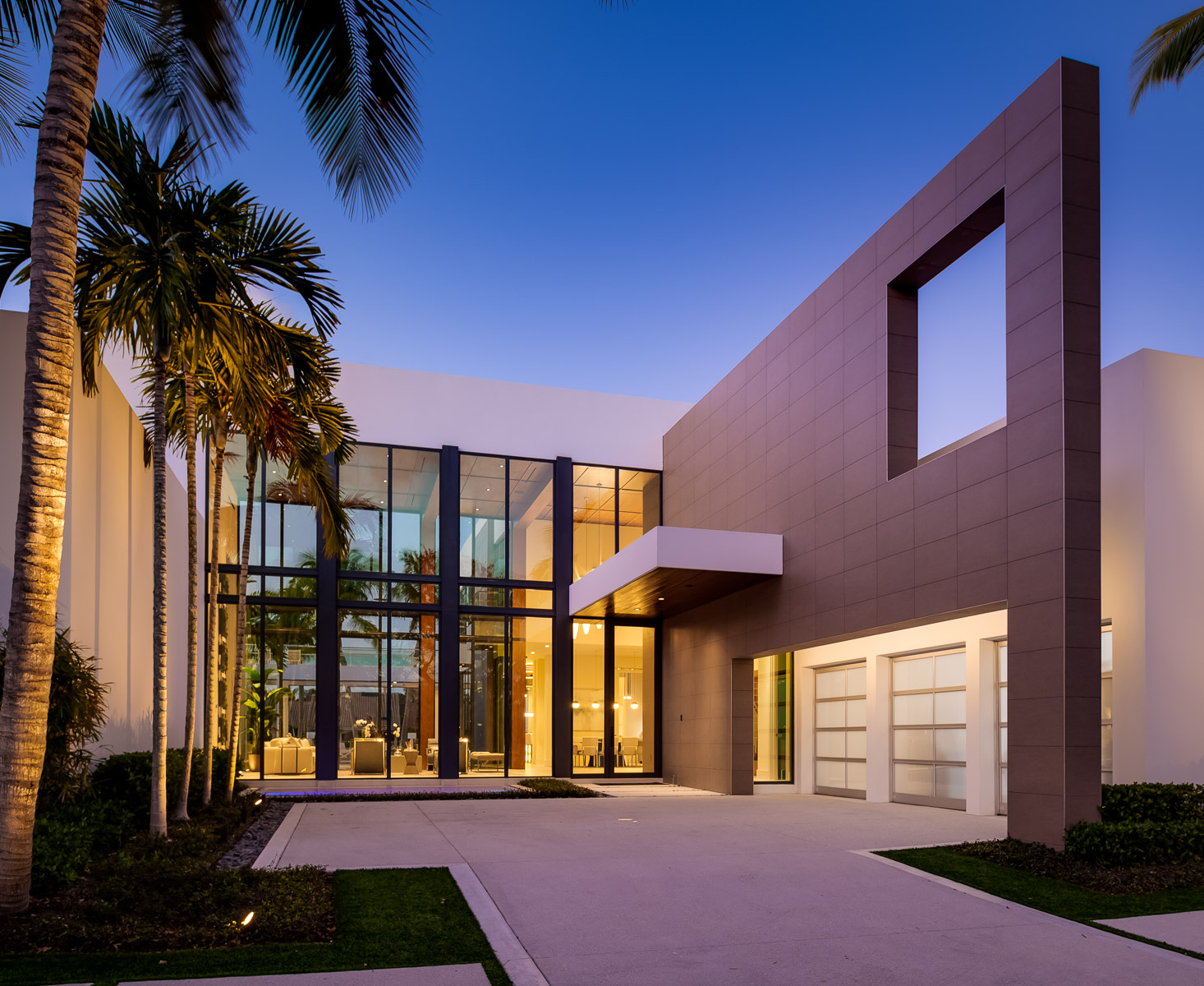a modern home with palm trees and a driveway.
