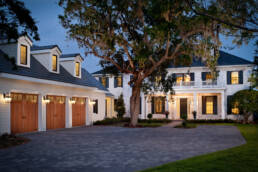 a white house with a driveway and garage at dusk.