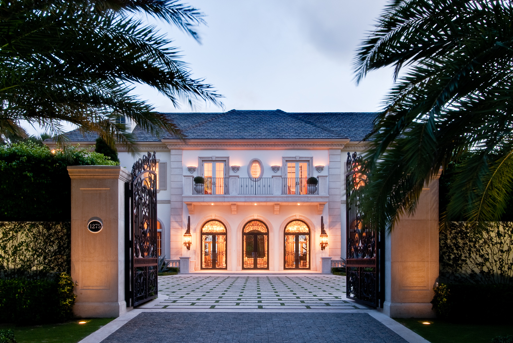 a mansion with a gated entrance and palm trees.