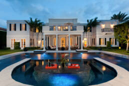 a large white mansion with a pool in the middle.