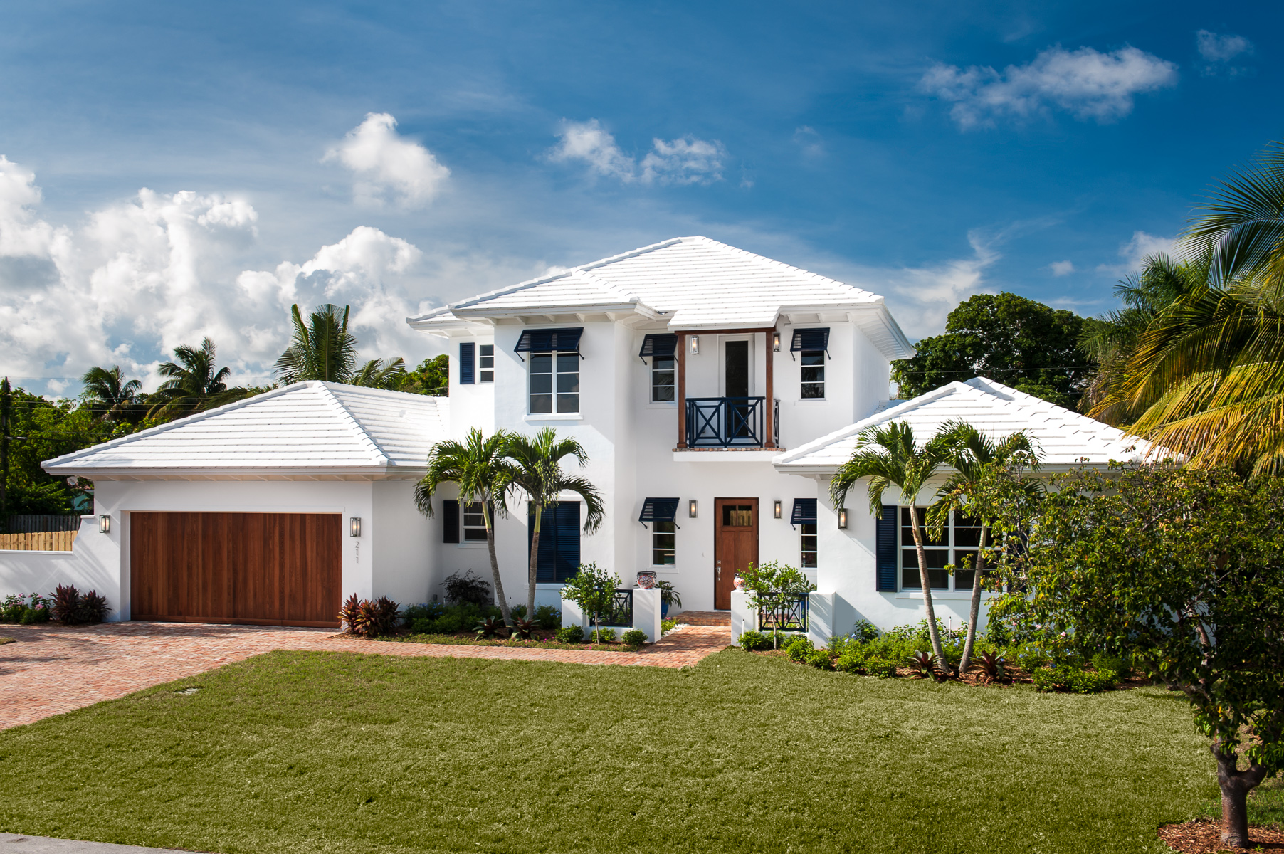 a white house with palm trees and a garage.