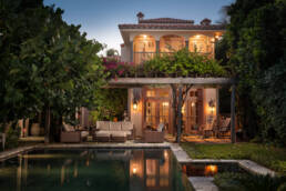 a house with a pool and patio at dusk.