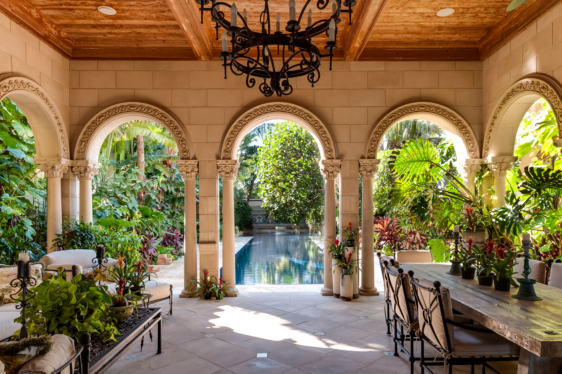 an arched patio with plants and a pool.