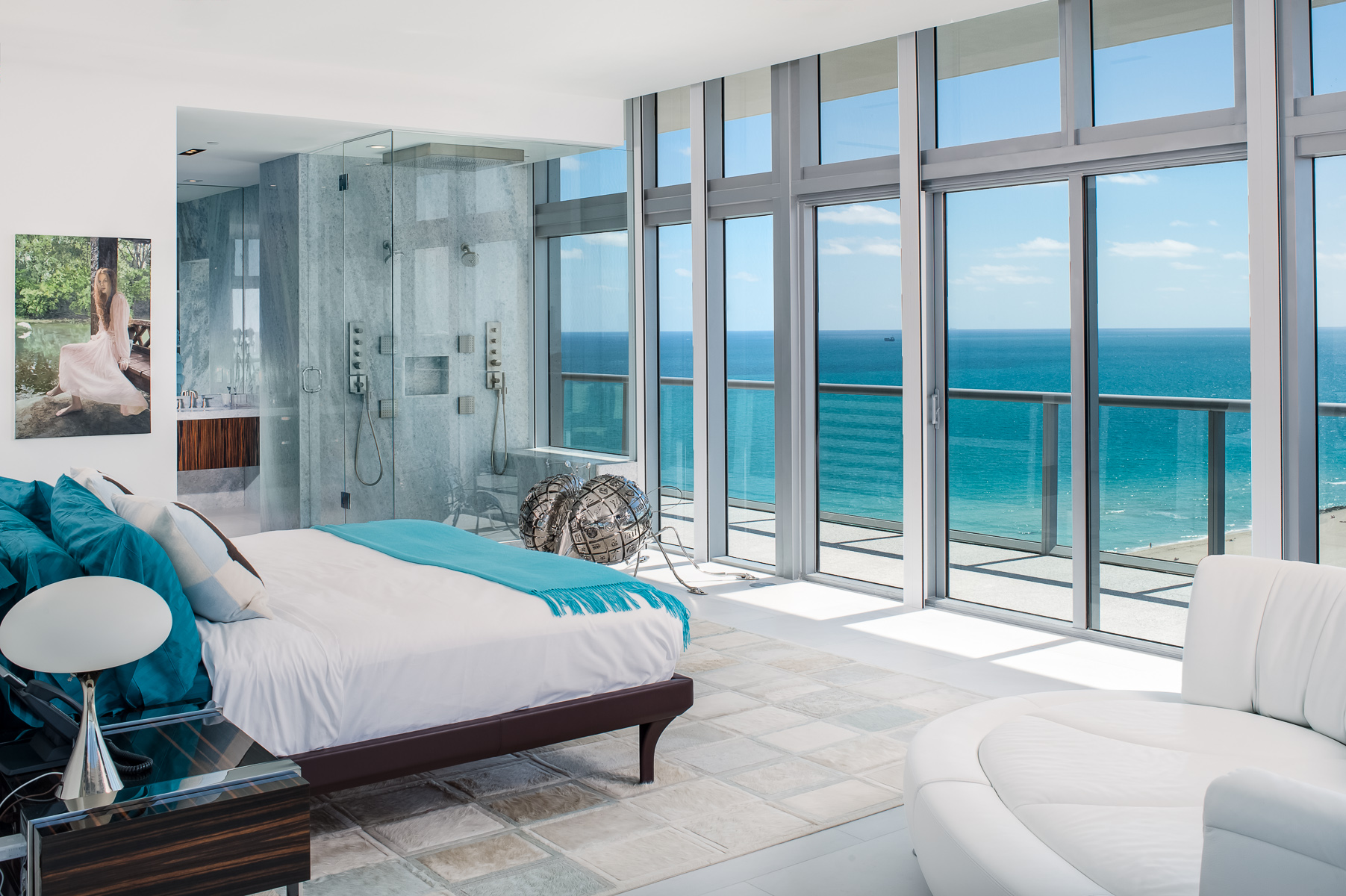 a bedroom with large windows overlooking the ocean.