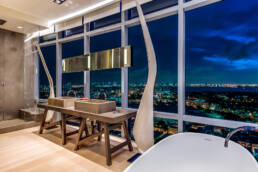 a modern bathroom with a view of the city at night shot by Charlotte architectural photographer
